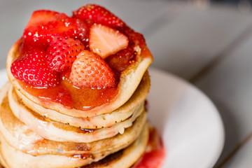 Delicious Strawberry Pancakes on a dark moody background, stunning breakfast with vibrant colors, white plate