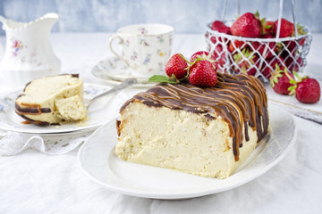 Traditional chocolate caramel cheesecake with fresh strawberries as top view on a plate