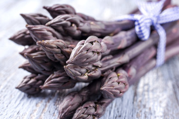 Roher lila Spargel als close-up auf Holz Board