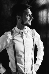 A close-up of a guy in stylish clothes who holds his hands on the waist on black and white photo