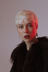 Beautiful blonde girl with short hair and makeup in a black fur coat