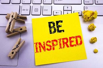 Hand writing text caption inspiration showing Be Inspired. Business concept for Inspiration and Motivation written on sticky note paper on the white keyboard background.