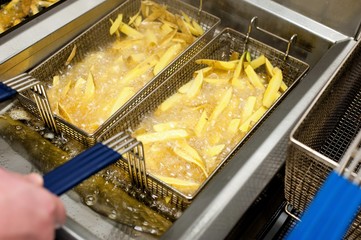 Slicing french fries from a commercial machine, frying potatoes