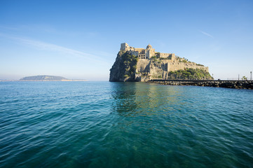 Fototapeta na wymiar Scenic morning view of the dramatic Aragonese Castle looming from its ancient mountaintop perch above the Mediterranean island of Ischia, Italy