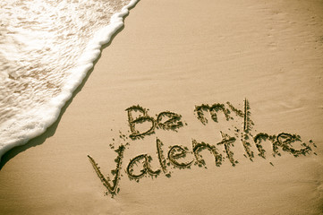 Be My Valentine message handwritten on smooth sand beach with oncoming wave