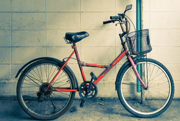 Fototapeta na wymiar An old red bicycle against a house exterior wall.vintage concept.