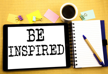 Be Inspired. Business concept for Inspiration and Motivation Written on tablet laptop, wooden background with sticky note, coffee and pen