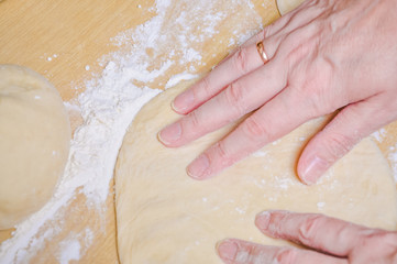 Woman doing manually the flat cake of leavened wheat dough