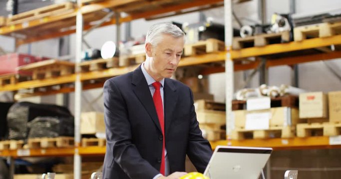 4k, Tired businessman with a concerned look working at a large warehouse.