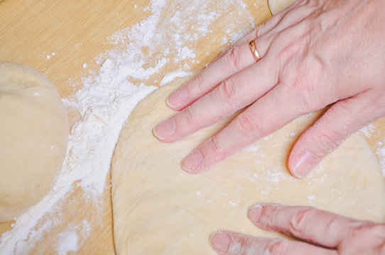 Woman doing manually the flat cake of leavened wheat dough
