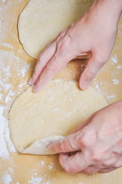 Woman doing manually the flat cake of leavened wheat dough