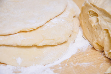 Raw wheat yeast dough rolled out into flat cakes on a table