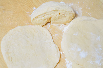 Raw wheat yeast dough rolled out into flat cakes on a table