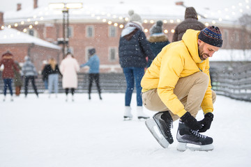Close up bearded man in yellow jacket, beige trousers and wearing black skates on ice rink /Man...