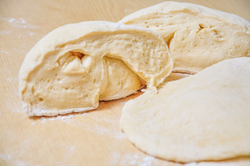 Raw wheat yeast dough rolled out into flat cakes on a table