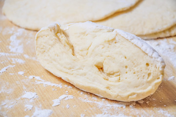Raw wheat yeast dough rolled out into flat cakes on a table