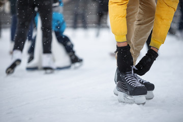 Close up of man hands wearing black skates on ice rink /Man tying black skates on ice rink in snowy...