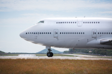 White airplane is taxiing to take off on sunny day /  wide-body aircraft on the runway is getting ready to take off, close-up/ Fuselage of the passenger double-decker aircraft close-up