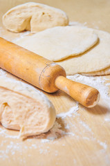 Rolled wheat dough and rolling pin on a wooden table