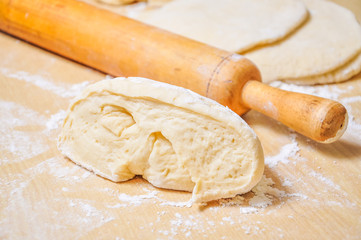 Rolled wheat dough and rolling pin on a wooden table