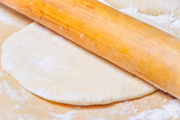 Rolled wheat dough and rolling pin on a wooden table