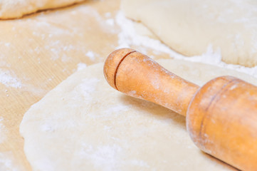 Rolled wheat dough and rolling pin on a wooden table