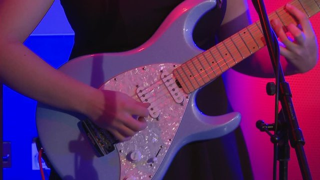 Girl plays light blue electric guitar with pearl pickboard