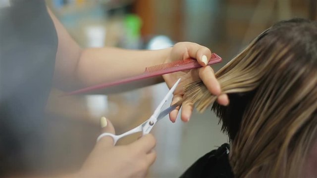 Coiffeur cutting hair ends with professional scissor, completing beautiful image