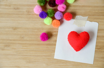 Red heart with note paper , colorful pom pom on wood background