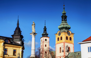 Obraz premium Colorful towers and roofs of main square in Banska Bystrica with blue sky and Mary / plague column and Catholic church in Barbican / Castle, Namestie Slovenskeho Narodneho Povstania, Slovakia Europe