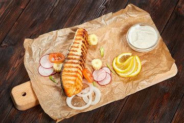 Grilled salmon fillet steak with vegetables, wooden board