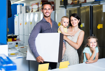 parents with two children shopping new electronics and holding box in shop of household appliances