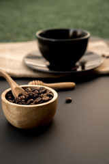 Top view a black cup of coffee americano and coffee bean grain on sack fabric put on black wood table background include copyspace for add text or graphic