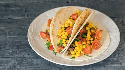 Freshly prepared Mexican tacos in a beautiful plate on a wooden table.