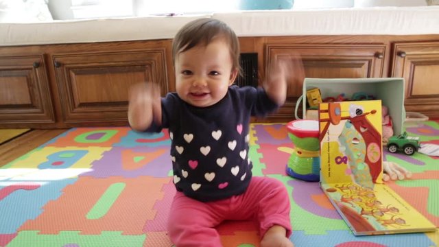 Cute baby dancing and flapping arms. Happily playing and laughing on floor with play mat.