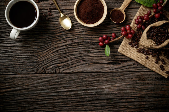 Top view mockup on wood background with a cup of coffee and red ripe coffee beans. Free space for your text.