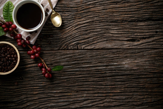 Top view mockup on wood background with a cup of coffee and red ripe coffee beans. Top view with copy space, flat lay.