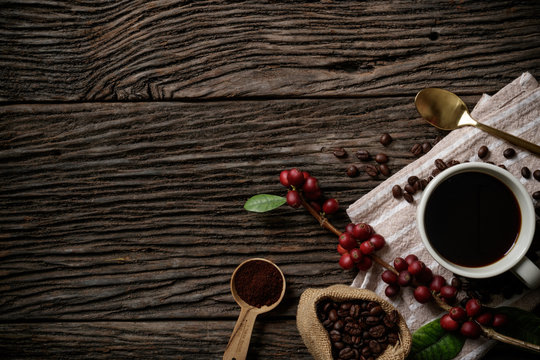Top view mockup on wood background with a cup of coffee and red ripe coffee beans. Free space for your text.