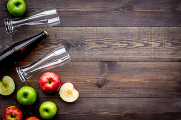 Apple cider. Low-alcoholic beveradge in dark bottle near beer glasses and fresh apples on dark...