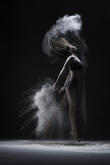 Slim girl jumping in white dust cloud view