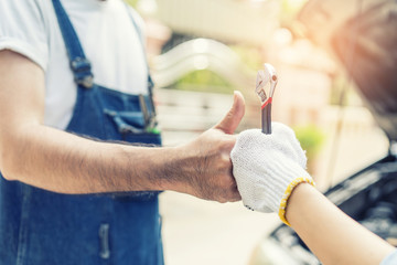 Mechanic hand checking and fixing a broken car in  garage.hand of mechanic with thumbs up and tool