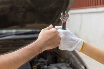 Mechanic hand checking and fixing a broken car in  garage.hand of mechanic with thumbs up and tool