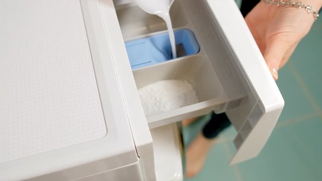 woman adding detergent to compartment in washing machine and closing drawer