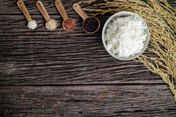 Rice in bowl and spoon on wooden desk with spike rice. Copy space for text.