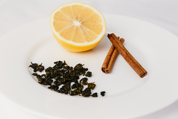 Fototapeta na wymiar lemon, cinnamon and green tea on a white plate