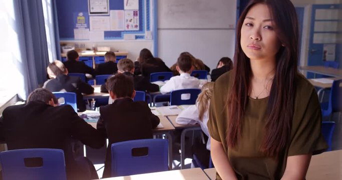 4K Portrait of depressed teacher in classroom with students working at their desks. Slow motion.