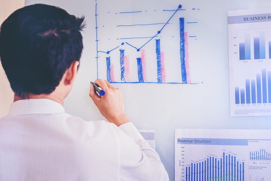 Businessman Writing Business Graph On White Board For Report Marketing Status