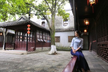a young woman in Chinese costume sitting in a Chinese traditional patio.