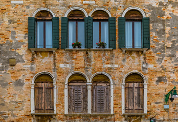 Fototapeta na wymiar Exterior of an old building with shutters and ornate windows in Venice Italy