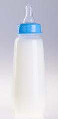 Baby bottle with milk on background
